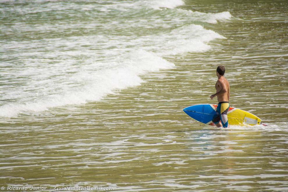 Imagem de um rapaz entrando com sua prancha na Praia de Jeribucaçu.